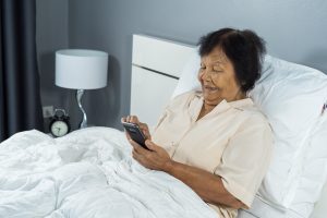 senior woman using mobile phone on bed