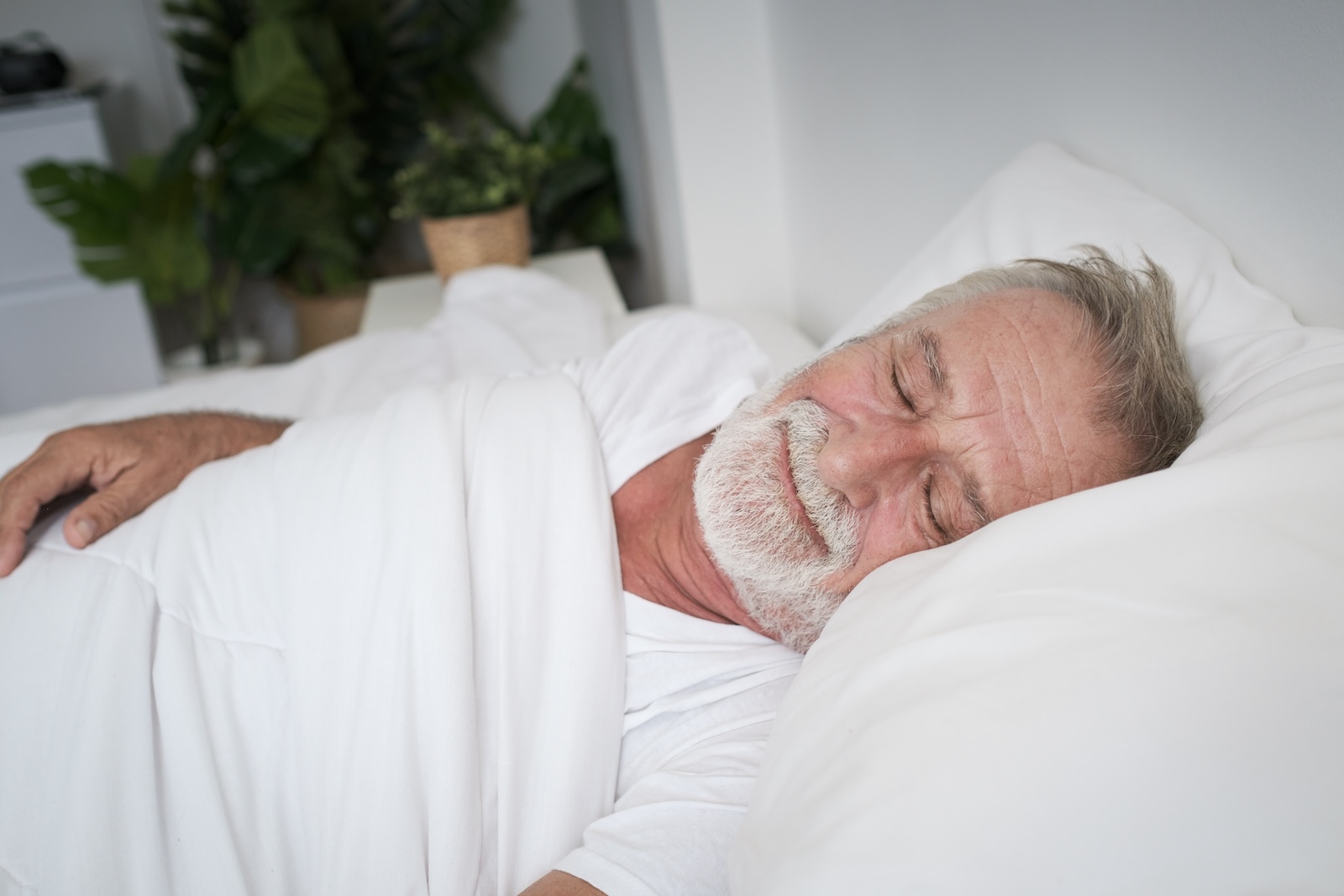 senior man sleeping alone and headache or dreaming nightmare on bed in room