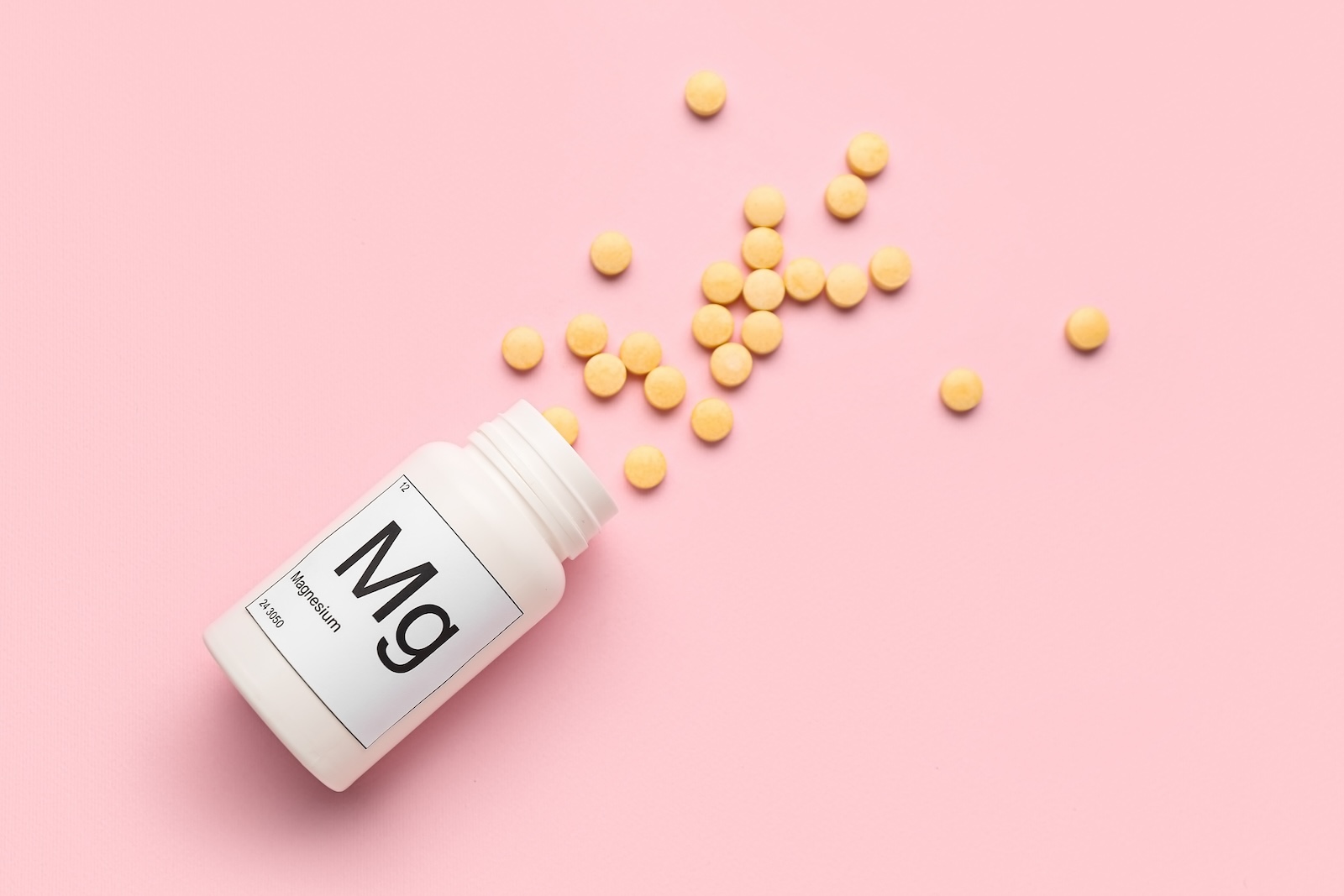 Bottle of magnesium pills on pink background