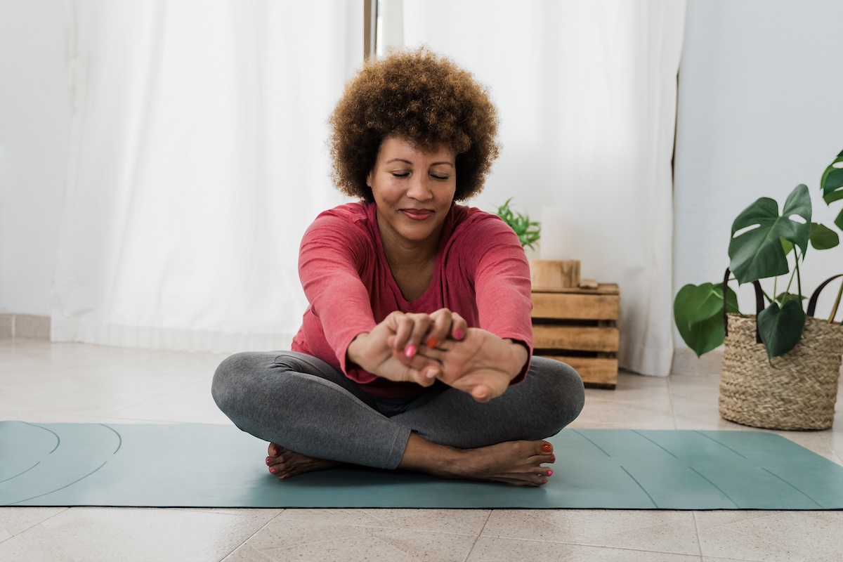 African senior woman doing yoga at home - Healthy lifestyle and mindfulness elderly concept - Focus on face